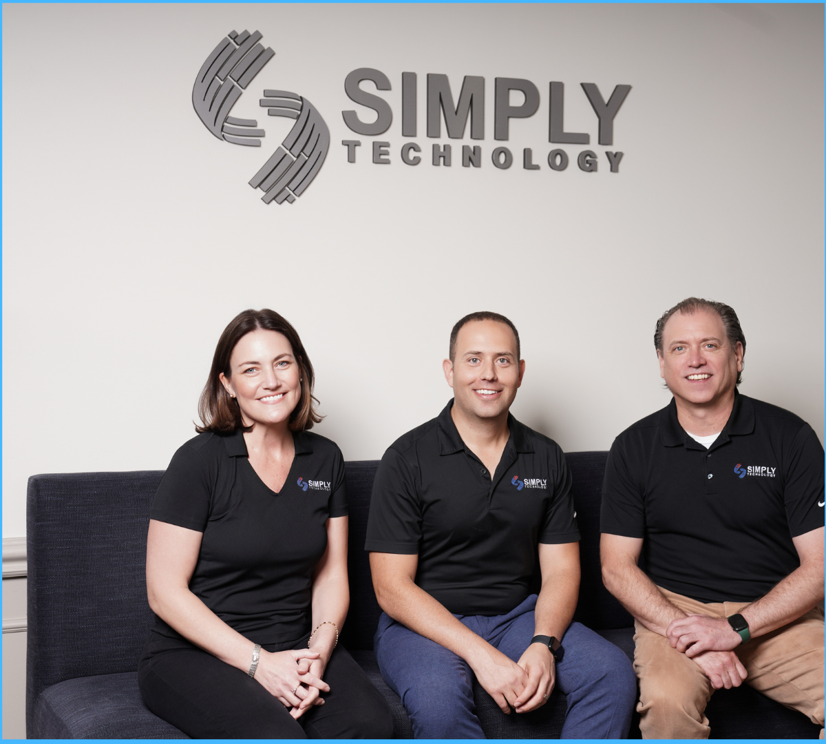 Three Simply Technology team members smiling and seated under the company logo.